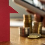 Maison, pièces de monnaie, une main qui tape sur les touches d'une calculatrices et documents financiers
